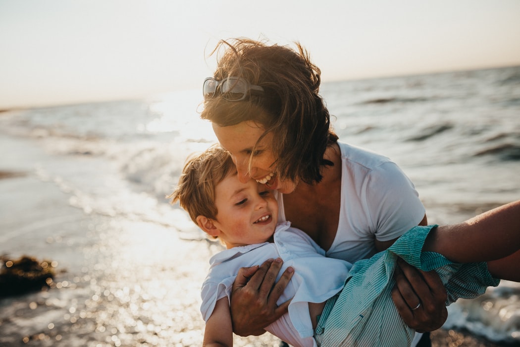 a mother and her baby playing happily on the beach